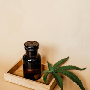 Glass Bottle and Marijuana Leaf on a Wooden Tray