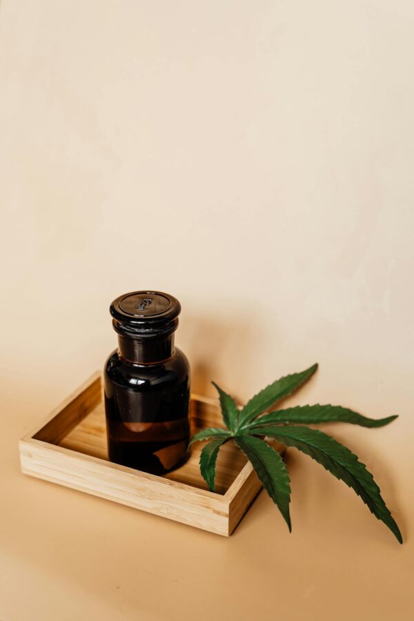 Glass Bottle and Marijuana Leaf on a Wooden Tray